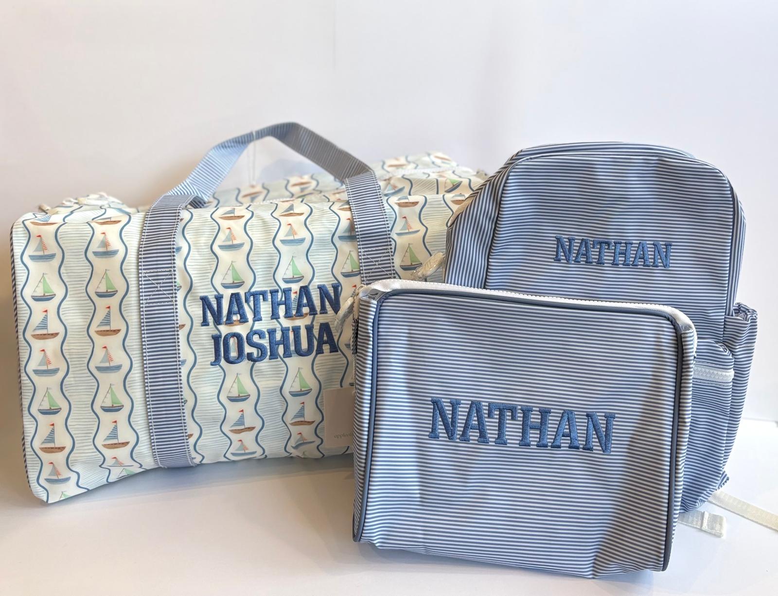 Two blue toiletry bags with embroidered names on a white background