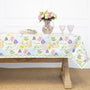 Floral patterned tablecloth on a wooden table with a vase of flowers and glasses.